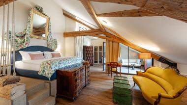Gemütliches Schlafzimmer mit Holzbalken und gelbem Sofa in Castel Sallegg