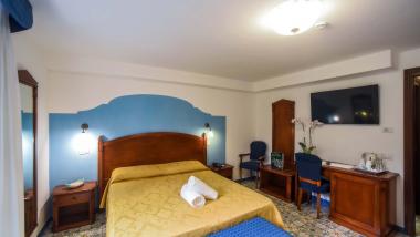 Camera dell'Hotel Amalfi con letto matrimoniale, mobili in legno e TV