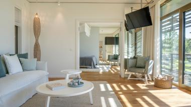 Helles, modernes Zimmer im Seezeitlodge Hotel & Spa mit Sofa und Balkon.