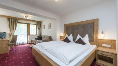 Zimmer im Hotel Waldsee mit Doppelbett, Sitzbereich und roten Teppich