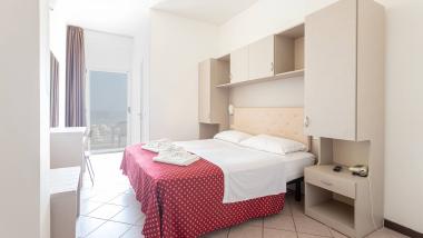 Camera luminosa con letto e copriletto rosso a fiori