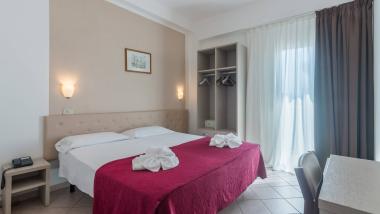 Camera d'albergo con asciugamani a forma di fiori sul letto e copriletto rosso