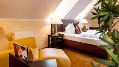 Gemütliches Zimmer mit Sessel und Bett im Burghotel Staufeneck