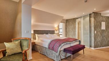 Modernes Schlafzimmer im Hotel Reppert mit Doppelbett und gemütlichem Sessel