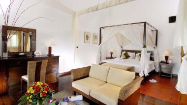 The Mangosteen Ayurveda & Wellness Resort room with canopy bed and cozy seating area