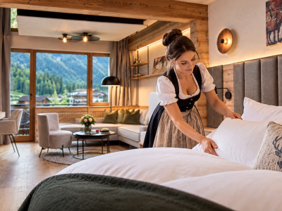 Frau richtet ein Bett im Hotel Jagdhof Pfurtscheller mit Bergblick
