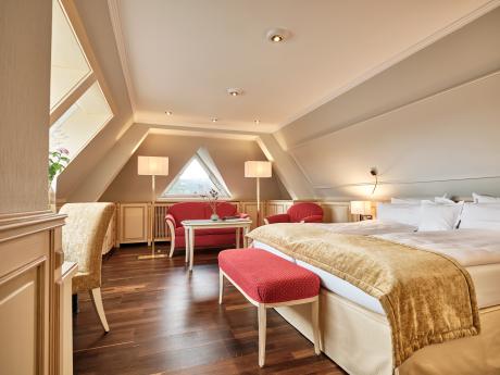Elegantes Hotelzimmer im Hotel Reppert mit Doppelbett, Sesseln und Dachfenster