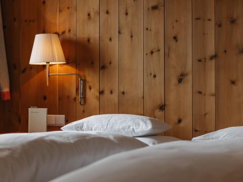 Gemütliches Hotelzimmer im Hotel Aurora mit Holzwand und weißer Bettwäsche