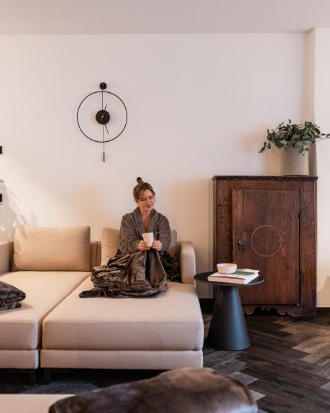 Lounge Schwarzer Adler mit Frau auf hellem Sofa neben einem dunklen Holzschrank