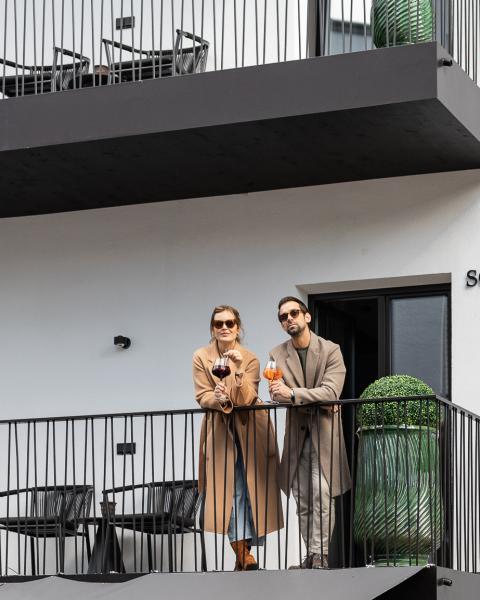 Zwei Personen auf einem Balkon neben dem Schriftzug Schwarzer Adler