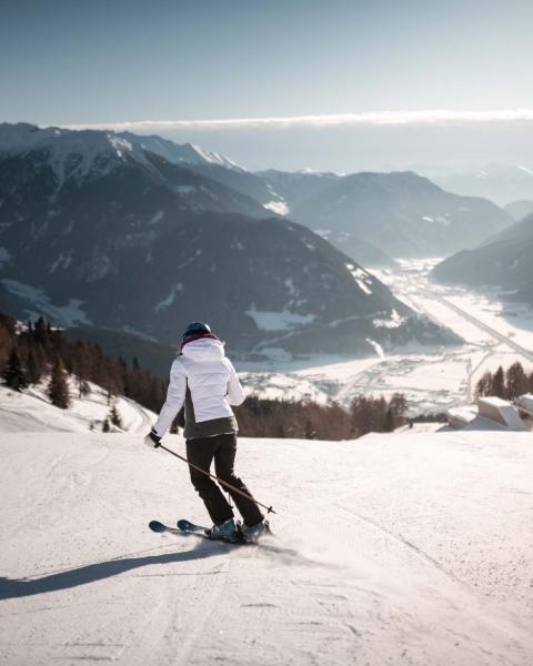 Schwarzer Adler: Skifahrer auf einer verschneiten Piste mit Alpenpanorama