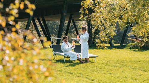 Gäste entspannen im Parc Hotel Florian Garten mit Getränken an sonnigem Tag