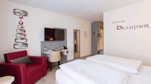 Modernes Hotelzimmer mit Doppelbett und rotem Sessel im Mythenresort Heimdall