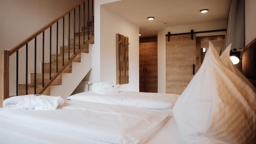 Schlafzimmer mit großem Bett und Treppe im Hotel Forstauerwirt