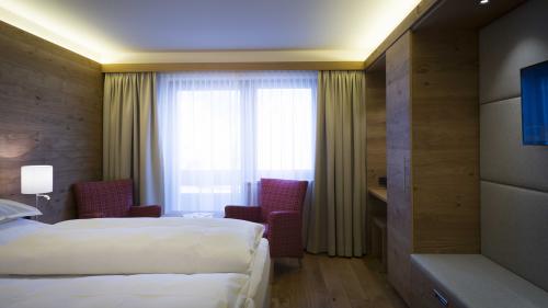 Hotel Panorama: Modernes Hotelzimmer mit Doppelbett, Sesseln und Fenster