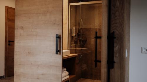 Badezimmer mit Schiebetür aus Holz und Glasdusche im Hotel Forstauerwirt