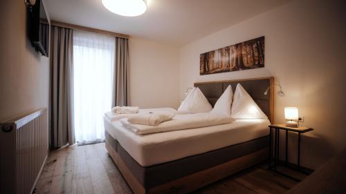 Schlafzimmer mit Doppelbett und Fenster im Hotel Forstauerwirt