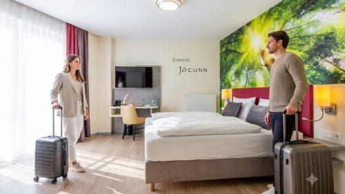 Paar mit Koffern im hellen Zimmer Jöcunn im Mythenresort Heimdall