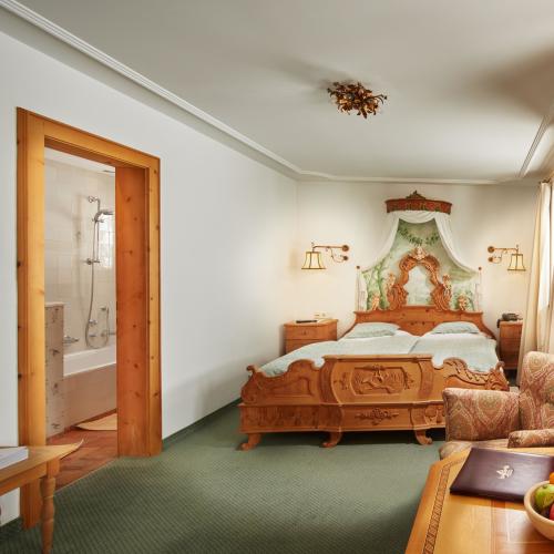 Hotel Post Lech: Traditionelles Doppelzimmer mit verziertem Holzbett und Bad