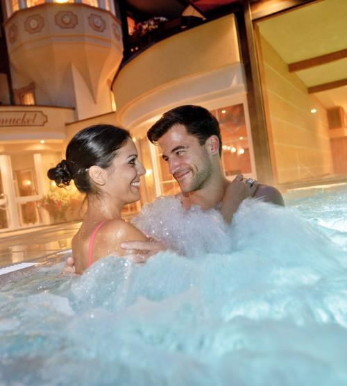Paar im Whirlpool im Resort La Ginabelle Zermatt bei Abendbeleuchtung
