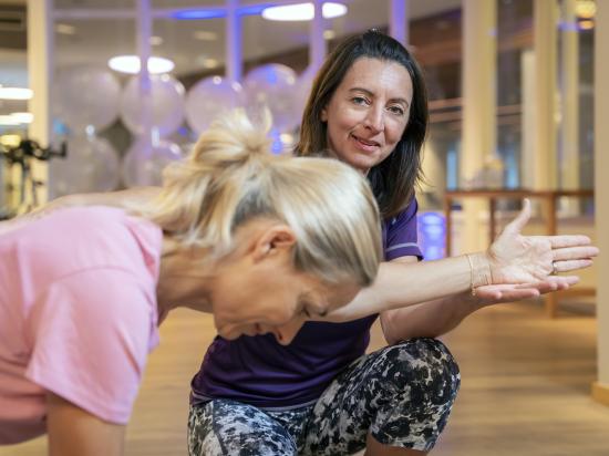 Sportlehrerin korrigiert Übung bei einer Frau
