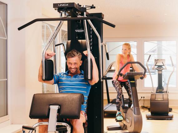 Mann trainiert an Gerät im Fitnessraum des Premium Activehotel Bergkönig