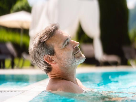 Mann entspannt im Pool des Schlosshotel Kitzbühel