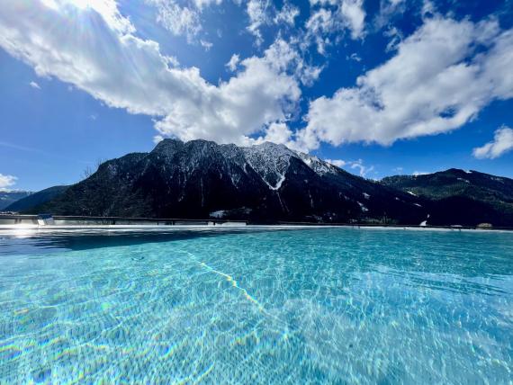 Blick auf den Pool und die Berge im Familienresort Buchau bei klarem Himmel