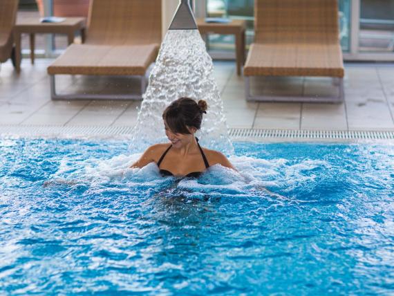 Donna si rilassa nella piscina con massaggio d'acqua da 7th Heaven Beauty & Wellness