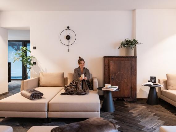 Lounge Schwarzer Adler mit Frau auf hellem Sofa neben einem dunklen Holzschrank