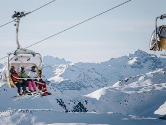 Naturhotel Die Waldruhe Gäste in Sessellift vor verschneiten Bergen