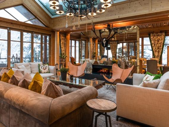 Warm, wood-paneled lounge with sofas, armchairs and mountain views at Hotel Gassner **** Superior
