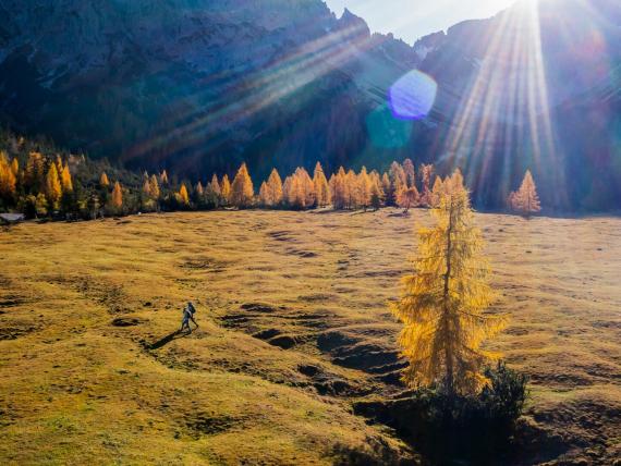 Krumers Alpin Wanderer auf herbstlicher Almlandschaft mit Sonne und Bergen