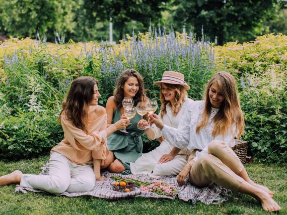 Vier Frauen genießen ein Picknick bei Krumers Alpin im Grünen.
