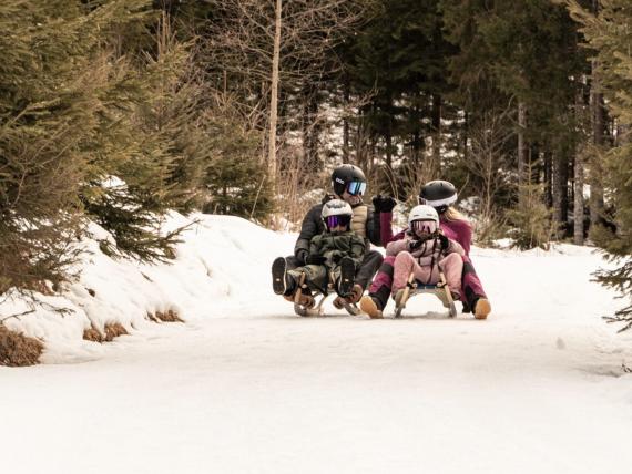Familie auf zwei Schlitten genießr Rodelspaß in der Ferienregion Nationalpark Hohe Tauern