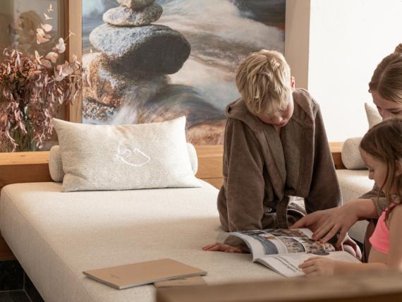 Family browsing a brochure on a lounge bed at Hotel Gassner **** Superior