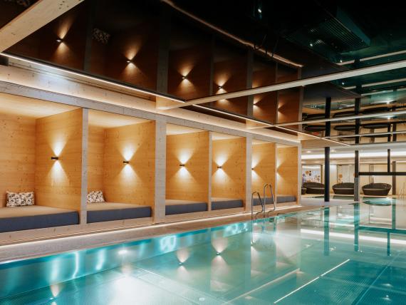Poolbereich im Familienresort Buchau mit Holzsitzecken und türkisfarbenem Wasser
