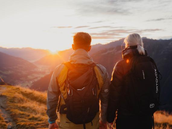 Paar wandert bei Sonnenaufgang Richtung Gipfel in der Region Nationalpark Hohe Tauern