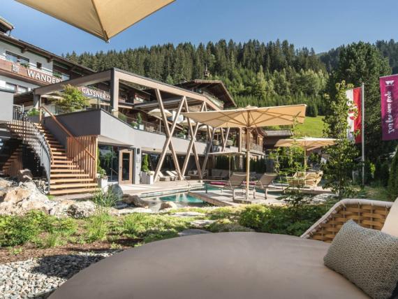 Außenbereich mit Pool und Sonnenschirmen im Hotel Gassner **** Superior vor Bergwald