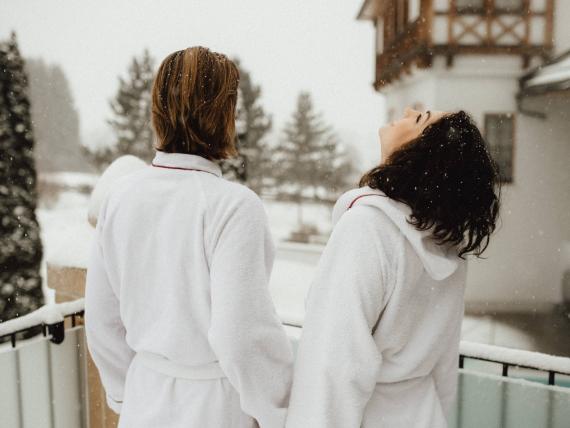 Paar im Bademantel auf Balkon im Schnee im Schlosshotel Kitzbühel
