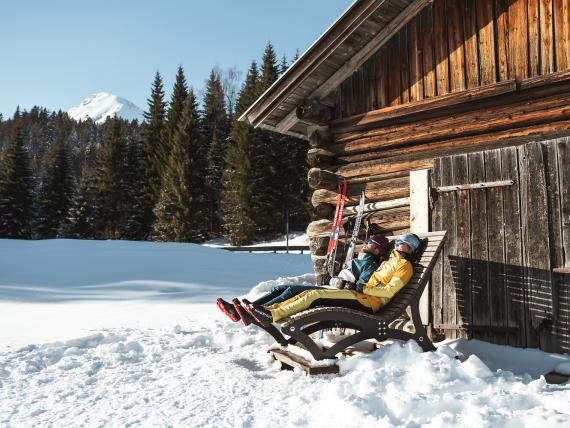 Gäste entspannen im Schnee vor einer Almhütte beim Biohotel Leutascherhof