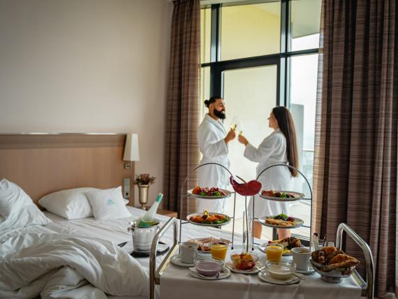 Paar im Bademantel stößt mit Wein im Parkhotel St. Leonhard Überlingen an
