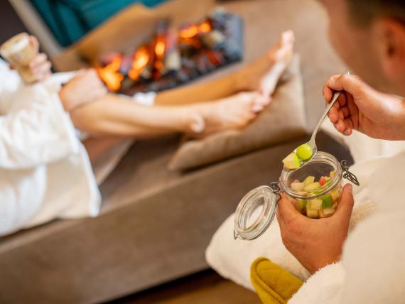 Entspannte Gäste im Bademantel beim Essen vor dem Kamin im Pfalzblick Wald Spa Resort