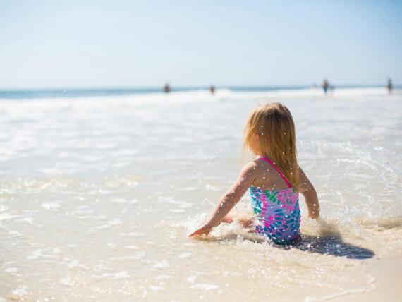 Bambina seduta nell'acqua bassa sulla spiaggia di Le Rose Nuove Viserba