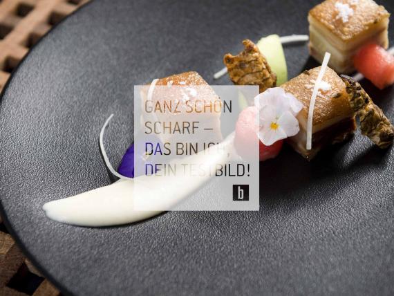 Gourmetgericht auf einem schwarzen Teller kreativ präsentiert.