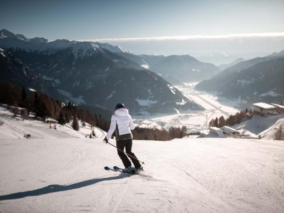 Schwarzer Adler: Skifahrer auf einer verschneiten Piste mit Alpenpanorama
