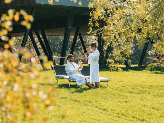 Gäste entspannen im Parc Hotel Florian Garten mit Getränken an sonnigem Tag