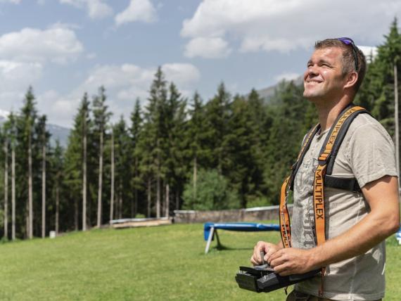 Mann mit Kameragurt im Grünen vor Wald im Hotel Gassner **** Superior
