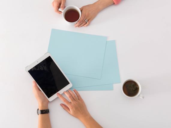 Tavolo con tovaglia blu e fiori, mare e spiaggia con ombrelloni sullo sfondo