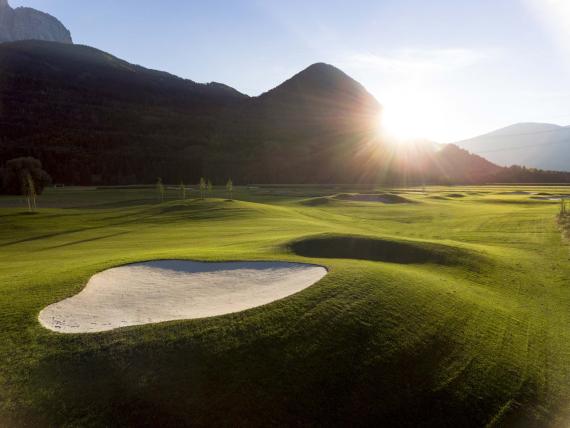 Der Dolomitenhof ***S Golfplatz mit Sandbunker und Bergen im Sonnenuntergang